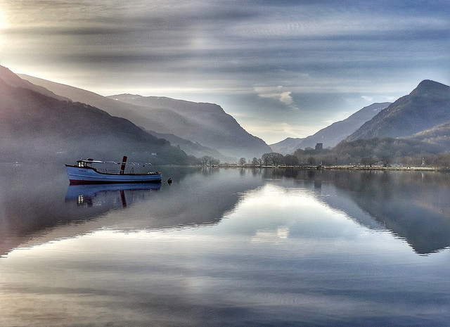 A boat floating on Llyn Padarn, with mountains beyond.