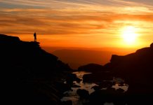 Sunset at Kinder Downfall with walker silhouetted against mountain backdrop